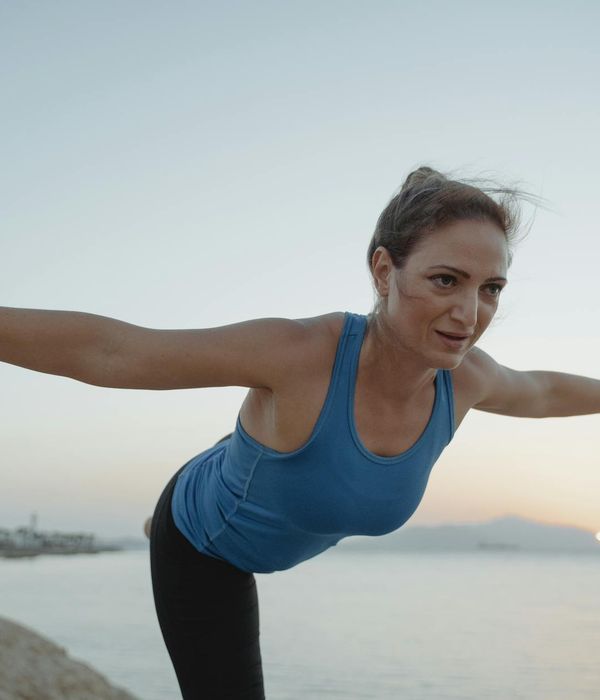 Person practicing an energetic yoga pose against a sunrise.